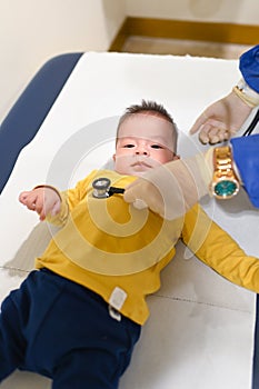 Doctor using stethoscope to listen breathing of a baby boy at the routine checkup at the doctors office in the hospital