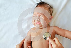 Doctor using a stethoscope to listen to baby`s chest checking heart beat