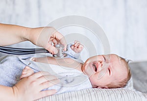 Doctor using a stethoscope to listen to kid`s chest checking heartbeat