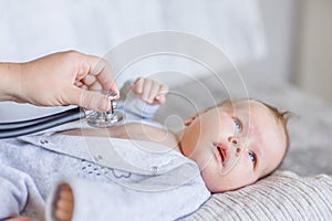 Doctor using a stethoscope to listen to kid`s chest checking heartbeat