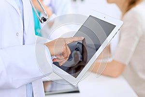Doctor using tablet computer, close-up of hands at touch pad screen