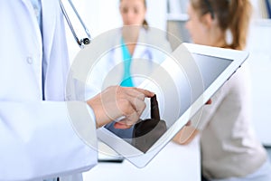 Doctor using tablet computer, close-up of hands at touch pad screen