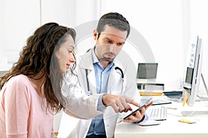 Doctor using tablet to inform patient photo