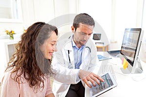 Doctor using tablet to inform patient photo