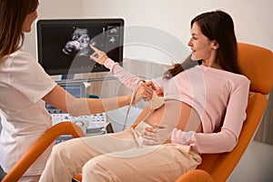 Doctor using ultrasound equipment for examining pregnant woman