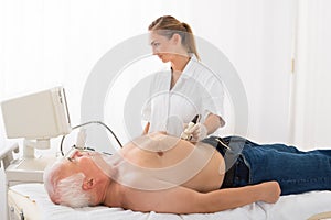 Doctor Using Ultrasound Scan On Abdomen Of Male Patient