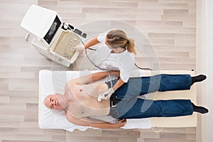 Doctor Using Ultrasound Scan On Abdomen Of Senior Male Patient