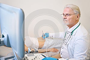 Doctor using ultrasound scan examining female patient in modern hospital