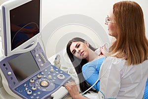 Doctor using ultrasound scanning machine examining female neck