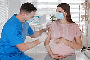 Doctor vaccinating pregnant woman against Covid-19 in clinic