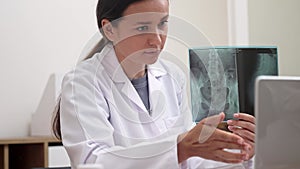 doctor on video call, displaying X-ray films on laptop, explains to patient as part of telemedicine