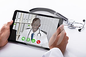 Doctor Video Conferencing With Male Colleague On Digital Tablet