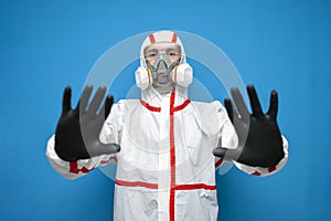 Doctor virologist in chemical protective suit shows hand stop sign on a isolated background, epidemiologist forbids leaving the