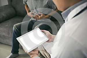 Doctor visited the patient while using tablet explaining about the patient stomach pain in the living room at home photo