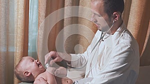 The doctor visits the baby patient at home. Baby crying and doctor with stethoscope