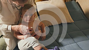 The doctor visits the baby patient at home. Baby with stethoscope