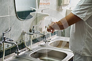 The doctor washes his hands with water in the preoperative room. Hand treatment before surgery