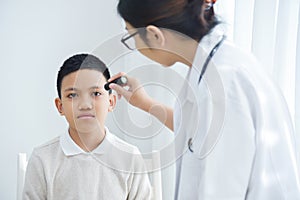 Doctor wear glasses checking a little boy patient eyes.