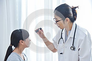 Doctor wear glasses checking a little girl patient eyes.