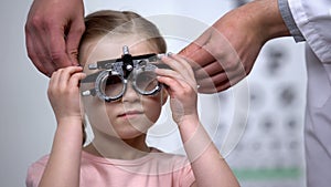 Doctor wearing at adorable child eye testing glasses to diagnose vision problems photo