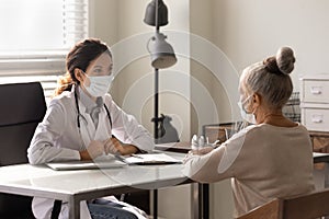 Doctor wearing face mask consulting mature woman at meeting