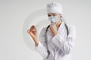 Doctor wearing face mask looking at measurement on medical thermometer over white background with copy space