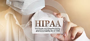 Doctor wearing face mask shows a card with the text HIPPA, The Health Insurance Portability and Accountability Act of 1996,. photo