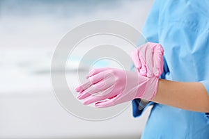 Doctor wearing medical gloves on color background.