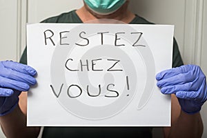 Doctor wearing medical mask to protect against the corona virus with prevention message : restez chez vous in french,