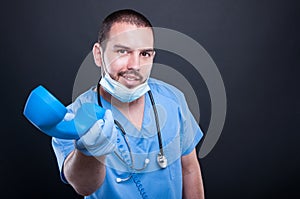 Doctor wearing scrubs handing telephone receiver and smiling