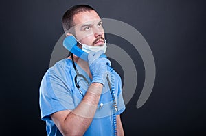 Doctor wearing scrubs holding telephone receiver