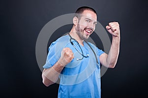 Doctor wearing scrubs with stethoscope making happy success gesture