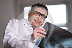 Doctor wearing a white lab coat examining X-ray images