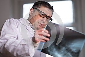 Doctor wearing a white lab coat examining X-ray images