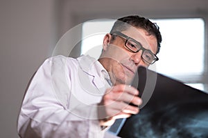 Doctor wearing a white lab coat examining X-ray images