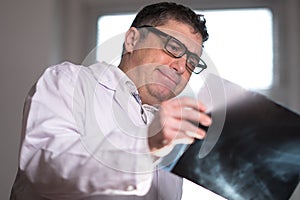 Doctor wearing a white lab coat examining X-ray images