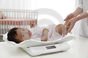 Doctor weighting African-American baby on scales photo