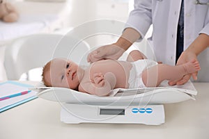Doctor weighting cute baby in clinic. Health care