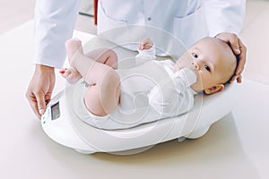 Doctor weighting cute baby at home photo