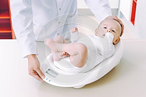 Doctor weighting cute baby at home photo