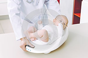 Doctor weighting cute baby at home photo