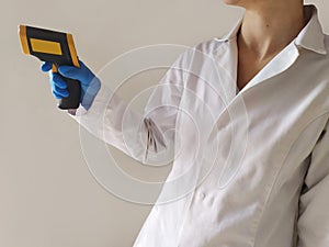 A doctor which dress a blue glove with a laser thermomether