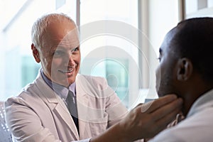 Doctor In White Coat Examining Male Patient In Office