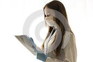 Doctor in a white coat and medical blue gloves records a patient`s medical history