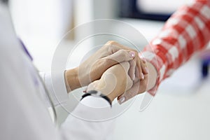 Doctor in white coat shaking hands with patient in clinic closeup