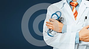 Doctor In White Coat With A Stethoscope Crosses His Arms Over His Chest Copy-space On Blue Background. Healthcare Medicine Concept