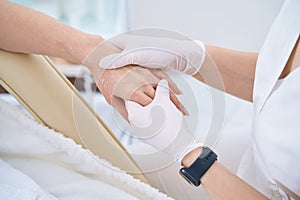 Doctor in white gloves gives a woman a hand massage photo