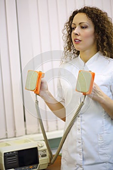 Doctor in white holds electroshock probes in photo