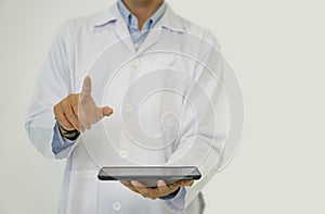 A doctor in a white lab coat holding blank screen tablet computer pointing finger toward with his hand. Portrait on white