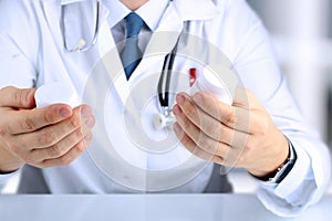 Doctor in a white labcoat choosing medicament between two drug packagings photo